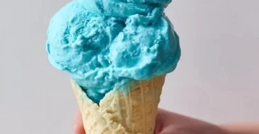 Scoop of Blue Moon Ice Cream in a waffle cone against a vibrant background