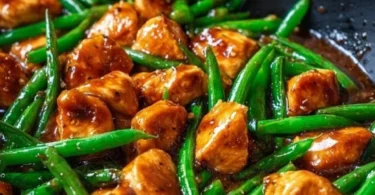 Grilled chicken breast served with fresh green beans on a plate.