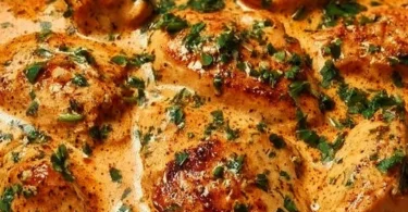 Creamy chicken dish served on a plate with herbs and vegetables