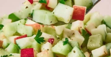 Fresh cucumber apple salad served in a bowl, drizzled with dressing