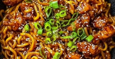 Bowl of Korean spicy chicken noodles garnished with green onions and chili flakes