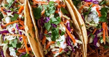 Pulled pork tacos topped with tangy slaw on a wooden board