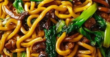 Plate of savory Shanghai fried noodles with colorful vegetables and proteins.